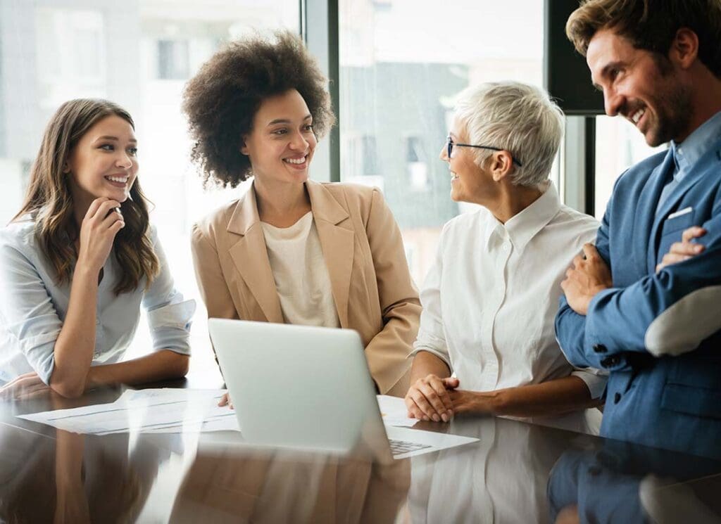 Business Health Insurance - Colleagues Laughing and Working Together in the Conference Room of a Modern Office with Lots of Light and Large Pane Glass Windows in the City