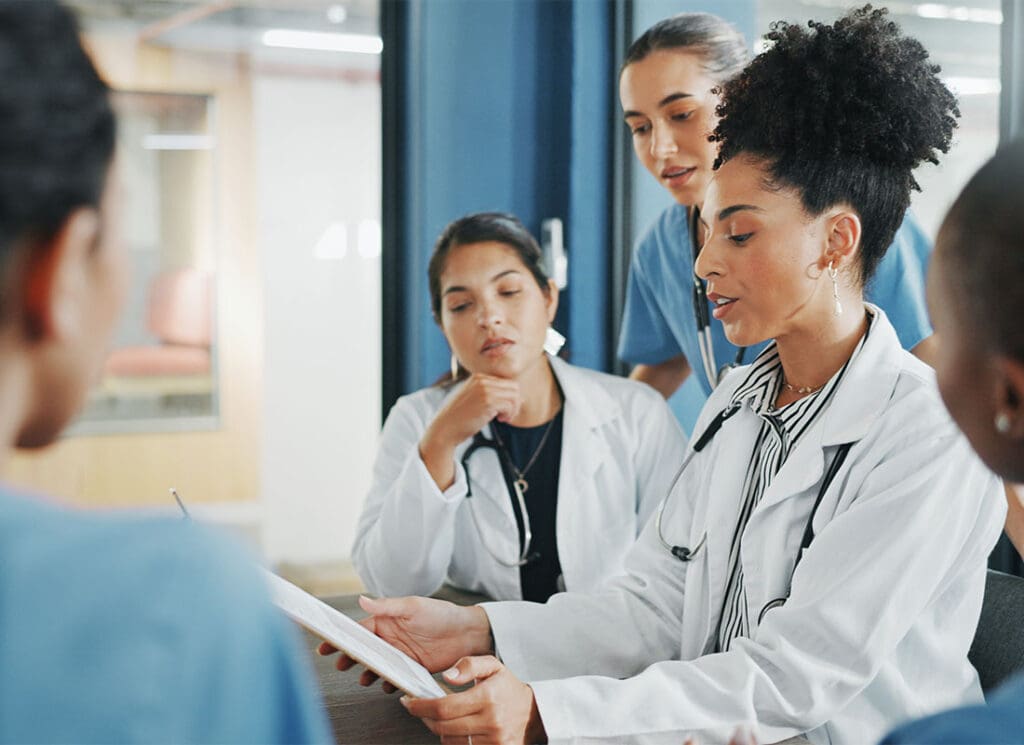 Traditional Group Health Insurance Coverages - Doctors and Medical Staff Meeting to Review Documents on Clipboard